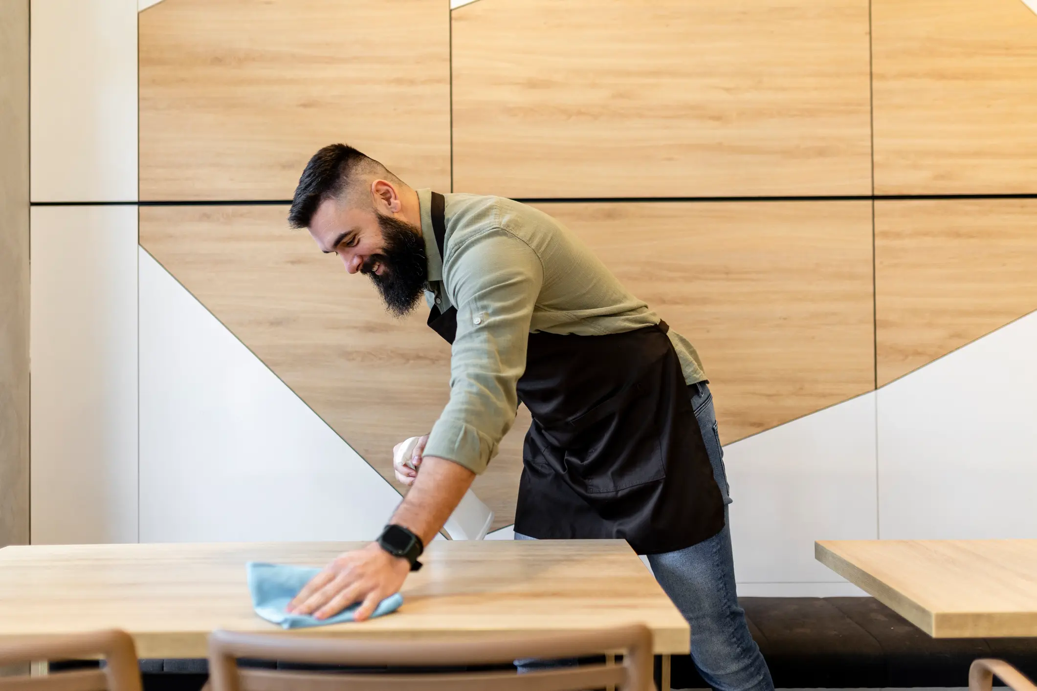 Serveur qui nettoie une table dans un restaurant avec un produit nettoyant